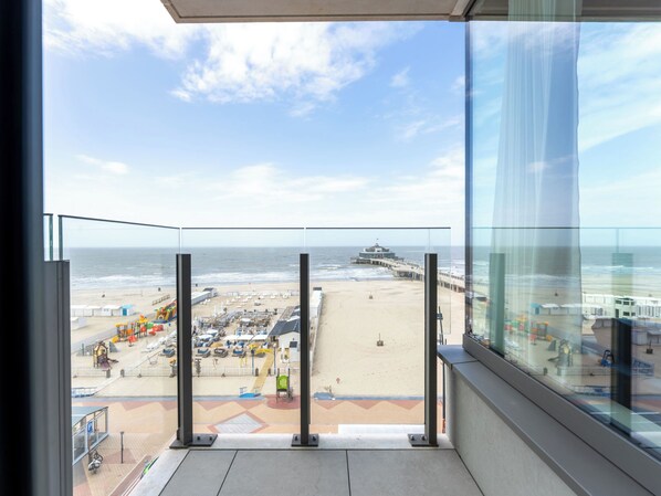 Ein Balkon mit Blick auf den Strand, einen Rettungsturm und einen Steg.