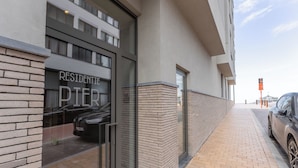 Un edificio moderno con entrada de vidrio, fachada de ladrillo y acera pavimentada.