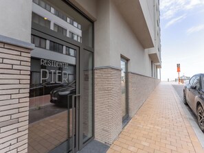Ein modernes Gebäude mit Glastür, Ziegelaußenwand und gepflastertem Bürgersteig.