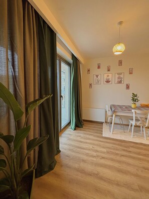 A room with a dining table, chairs, a hanging light fixture, a radiator, and a window with curtains. - 10 Mins to Takism - Central & New Modern Flat (Istanbul)