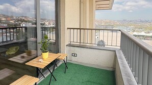A balcony with a green artificial turf floor, a wooden table, and a potted plant. - 10 Mins to Takism - Central & New Modern Flat (Istanbul)