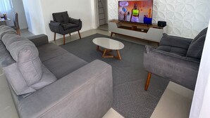 Ein modernes Wohnzimmer mit einem Ecksofa, einem Couchtisch, einem Fernseher und einer Wand mit Muster.