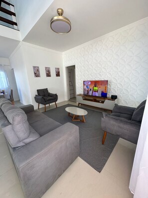 Ein modernes Wohnzimmer mit einem Ecksofa, einem Couchtisch, einem Fernseher und einer Wand mit Muster.