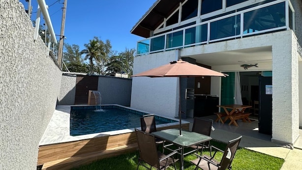 Ein modernes, zweistöckiges Haus mit Swimmingpool, Außenbereich und überdachter Terrasse.