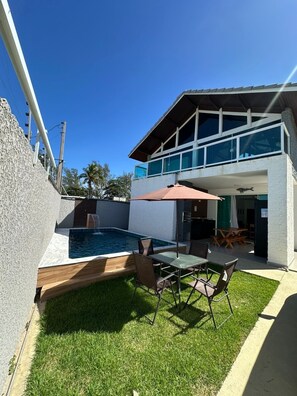 Ein modernes, zweistöckiges Haus mit Swimmingpool, Außenbereich und überdachter Terrasse.