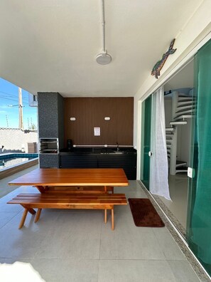 Eine moderne Küche mit Holztisch und Bänken, einer Glastür zum Balkon und einem Pool im Hintergrund.