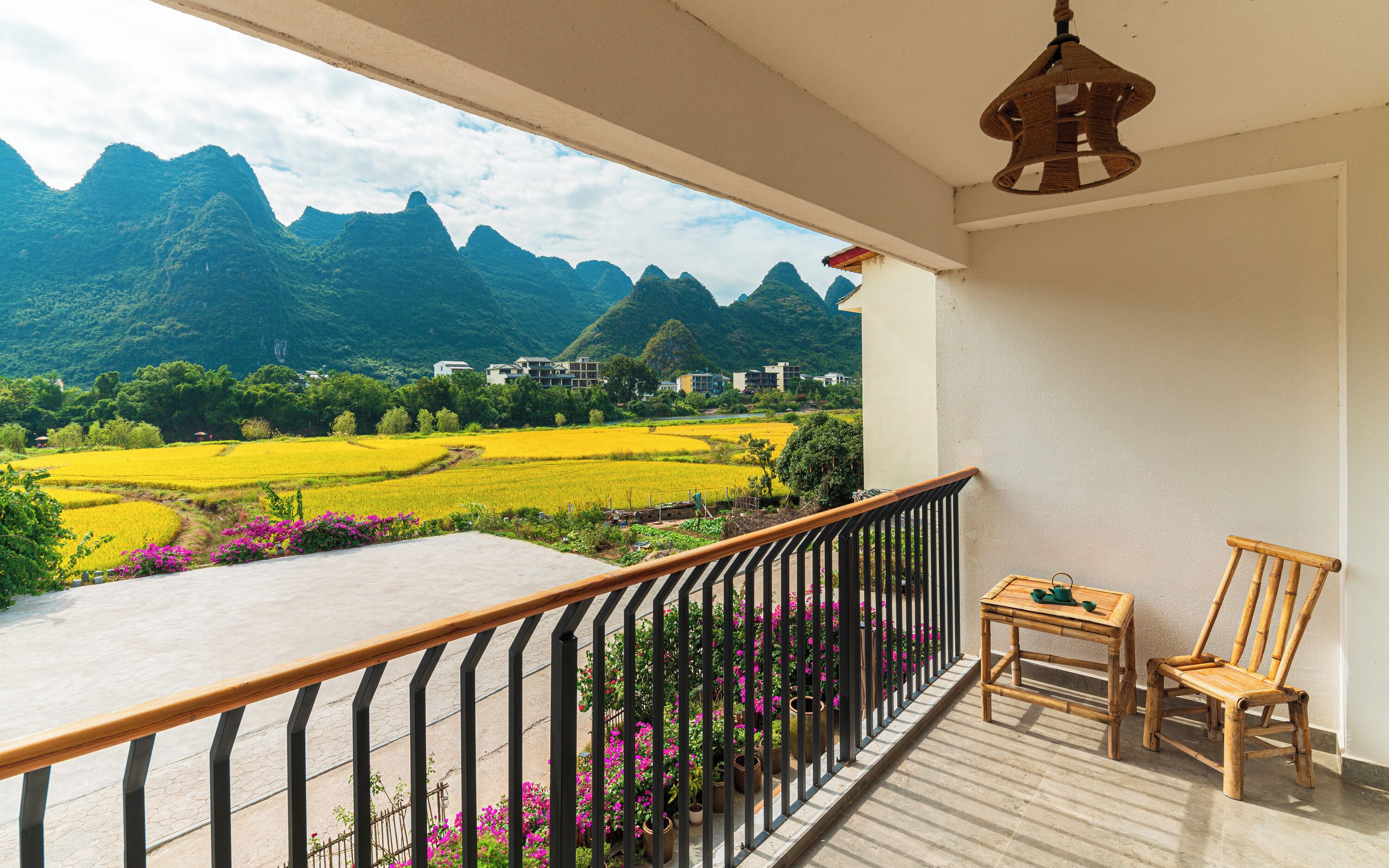 Un balcón con vistas a montañas, una mesa y una silla.