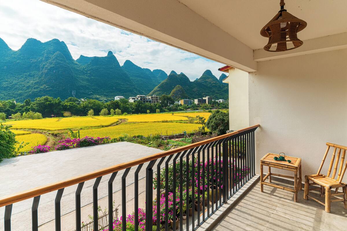 Un balcón con vistas a montañas, una mesa y una silla.