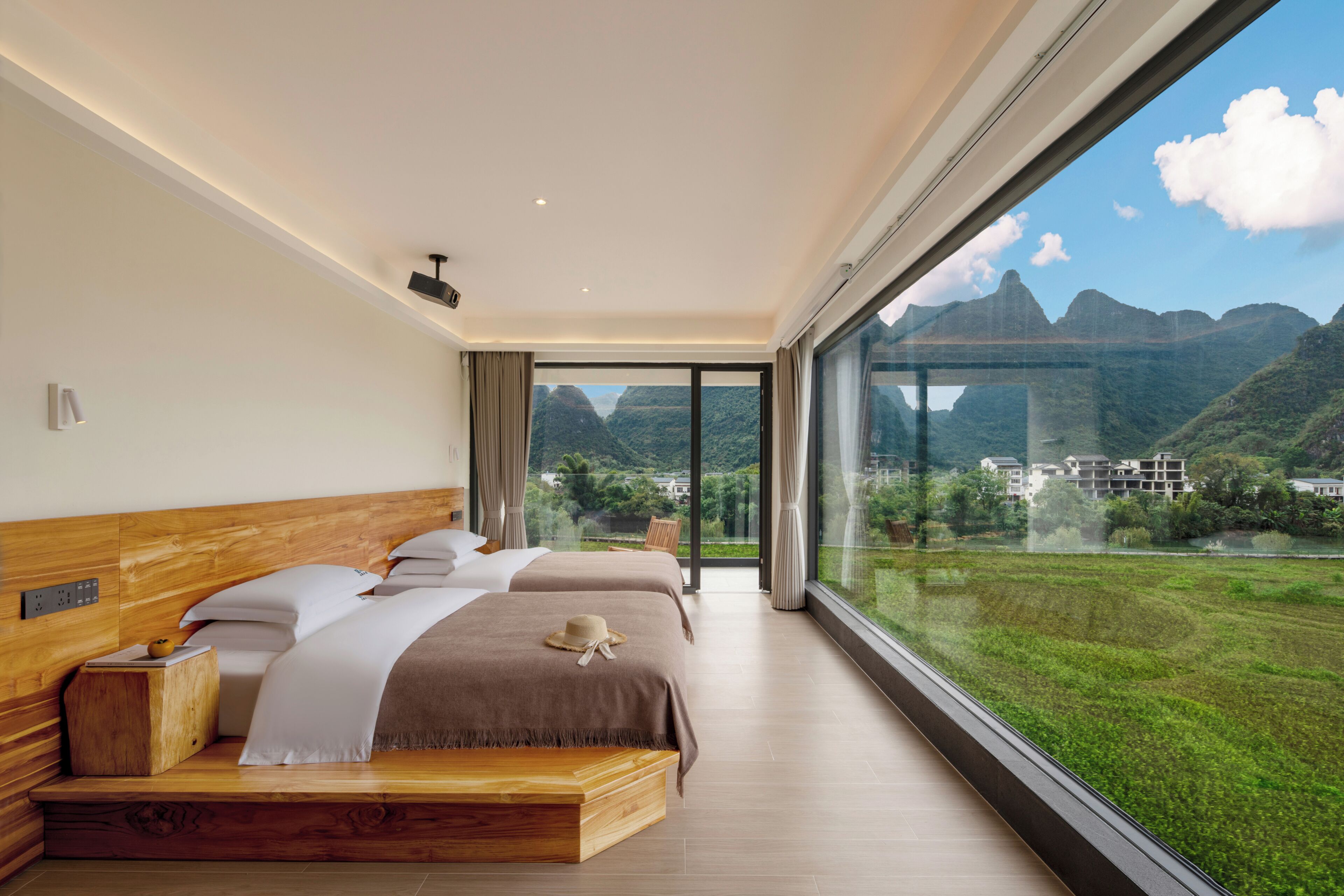 Ein Schlafzimmer mit großem Fenster, zwei Betten und Bergblick.