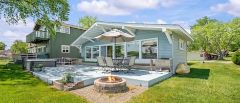 Ein Haus mit überdachter Terrasse, Sitzgelegenheiten im Freien und einer Feuerstelle.