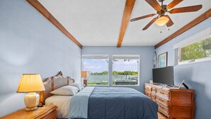 Un dormitorio con cama, cómoda de madera, televisor y ventilador de techo.