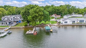 A lakeside property with a dock, a covered boat launch, and a large tree.