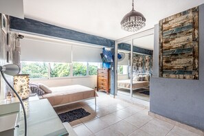 Ein Schlafzimmer mit Bett, Kommode und großem Fenster.