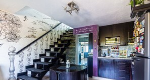 Eine moderne Küche mit dunklen Holdekor-Schränken, einem Edelstahl-Kühlschrank und einer Wand mit Vogelmotiv.