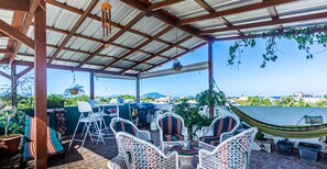 Eine Terrasse im Freien mit Korbmöbeln, einer Hängematte und Blick aufs Meer.