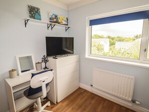 A child's bedroom with a desk, chair, TV, and artwork on shelves. - 1 Rosemount Garden Villas (Tenby)