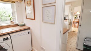 Een keuken met een vaatwasser, een raam met een plant, en lijstwerk aan de muur.