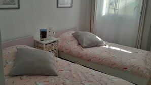 Une chambre à coucher avec deux lits, chacun étant équipé d’un oreiller et d’une table de chevet avec une lampe.