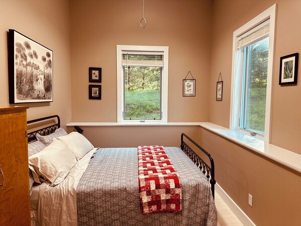 Un dormitorio con cama, ventana con persianas e imágenes enmarcadas en la pared.