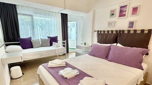 Una habitación de hotel con cama, asiento junto a la ventana, mesita de noche y lámpara en el techo.