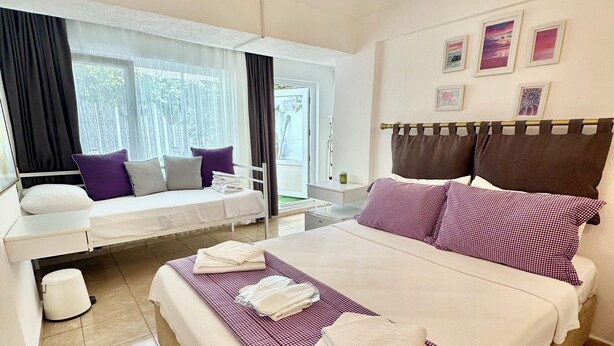 A hotel room with a bed, a window seat, a bedside table, and a ceiling light fixture.