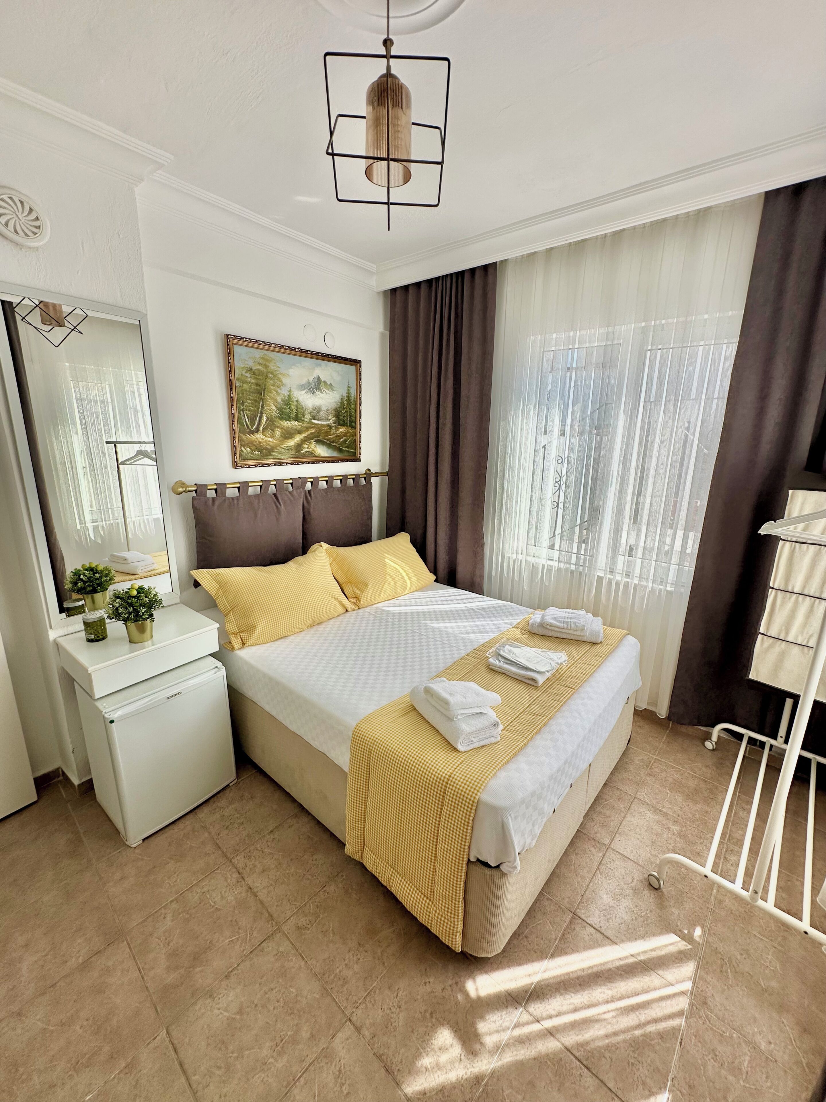 Habitación de hotel con cama, mesita de noche, espejo y un cuadro en la pared.