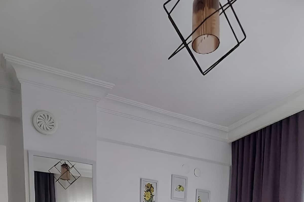 Ein Schlafzimmer mit Bett, Nachttisch, Spiegel und einer Pendelleuchte.