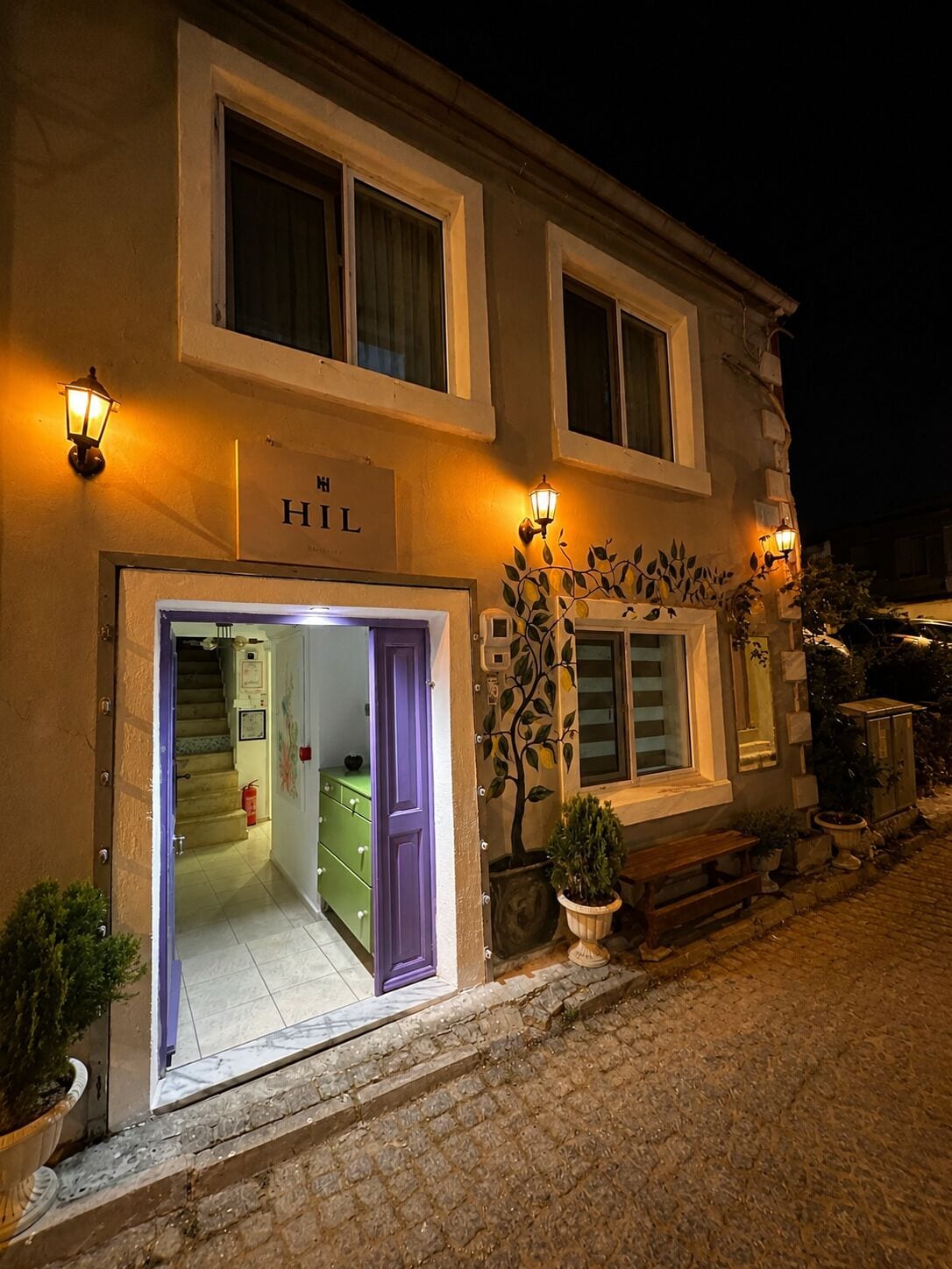 Entrada de un hotel con un letrero que dice 'HIL' y una escalera que conduce al interior.