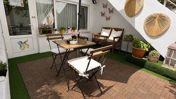 An outdoor patio with a table and chairs, surrounded by a brick floor and green artificial grass.