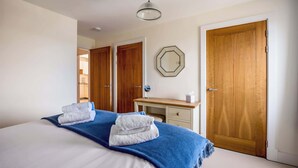A hotel room with a bed, a desk, a mirror, and two wooden doors. - Coastal Retreat - Spacious Apartment on Poole Quay (Poole)