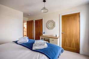 Ein Hotelzimmer mit einem Bett, einem Schreibtisch, einem Spiegel und zwei Holztüren.
