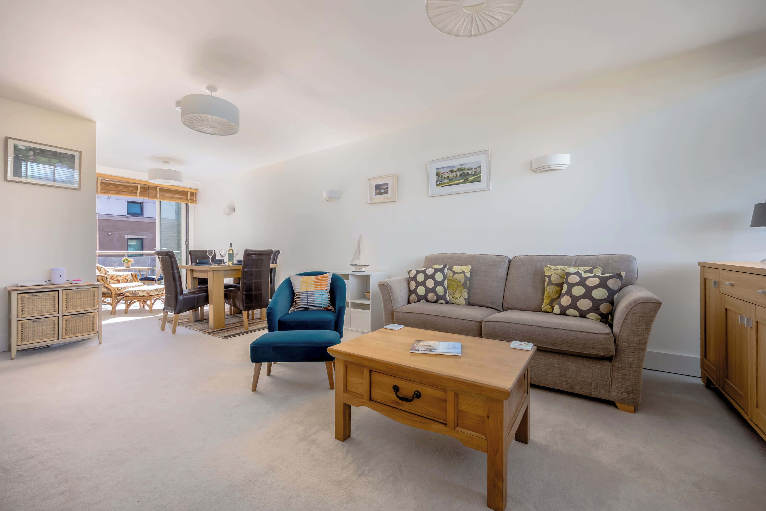 A living room with a sofa, coffee table, and a dining area with chairs and a table.