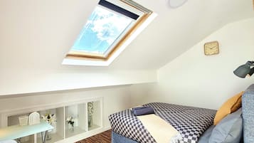 A compact room with a bed, a desk, and a skylight.