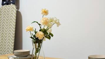 A dining table with a vase of flowers, bowls, and salt shakers.