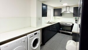 Une cuisine moderne équipée d’un lave-linge Bosch, d’un four encastré et d’un four à micro-ondes.