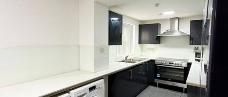 A modern kitchen with a Bosch washing machine, a built-in oven, and a microwave.