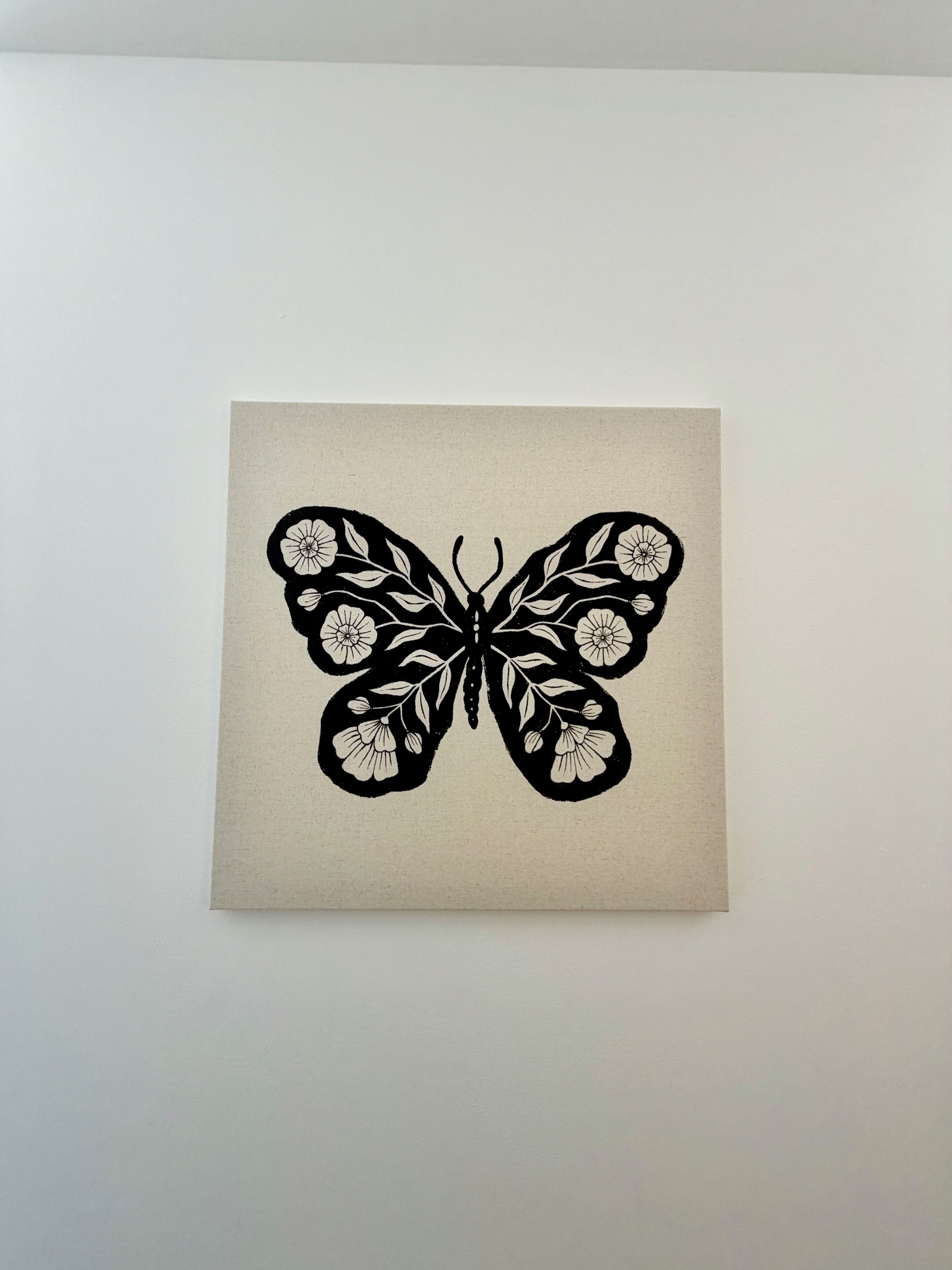 A square artwork of a butterfly with floral patterns.