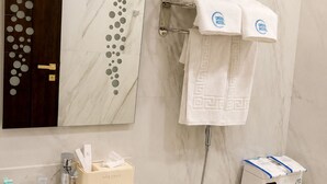 A bathroom with a marble sink, a mirror, a towel rack with two towels, a toilet, and a shower.