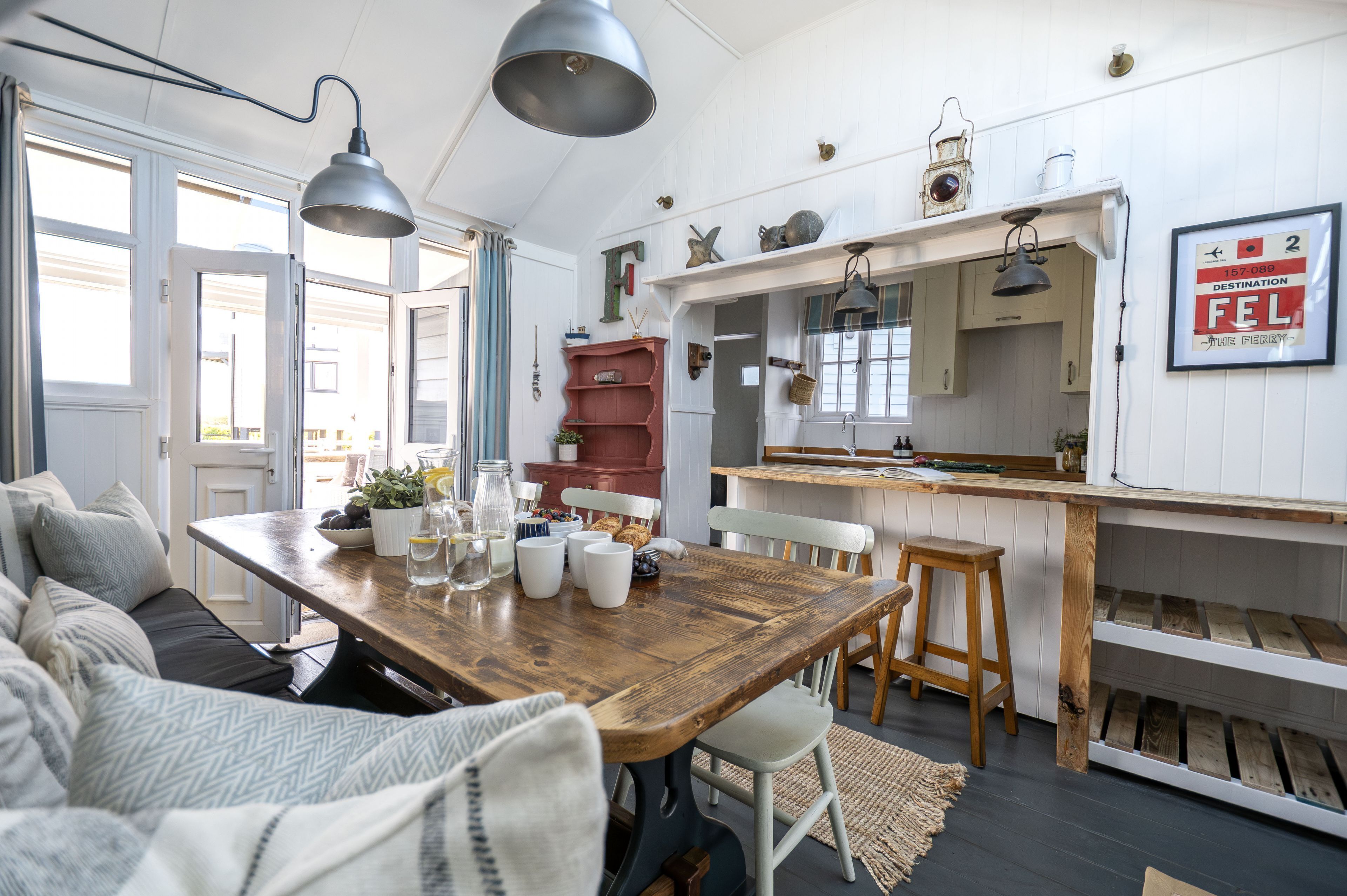 A cozy living room with a wooden dining table, a sofa, and a kitchen area with a wooden counter and cabinets.