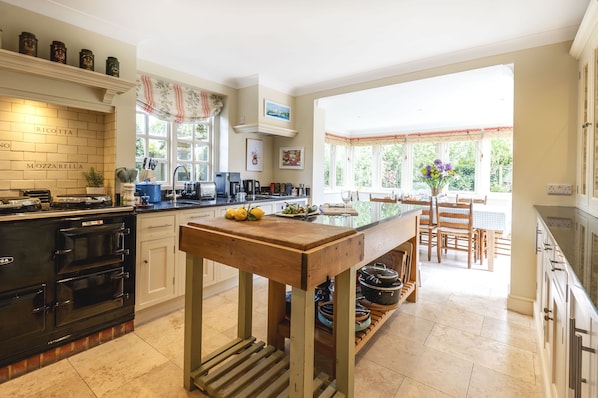 A kitchen with a wooden island, black stove, white cabinets, and a dining area with a table and chairs.