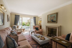 A living room with a sofa, armchairs, a coffee table, a fireplace, and a dining area with a table and chairs.