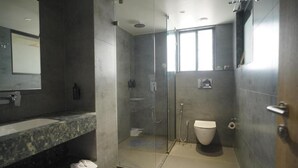Ein modernes Badezimmer mit einer gläsernen Duschkabine, einer Toilette und einem Waschbecken mit Marmorplatte.