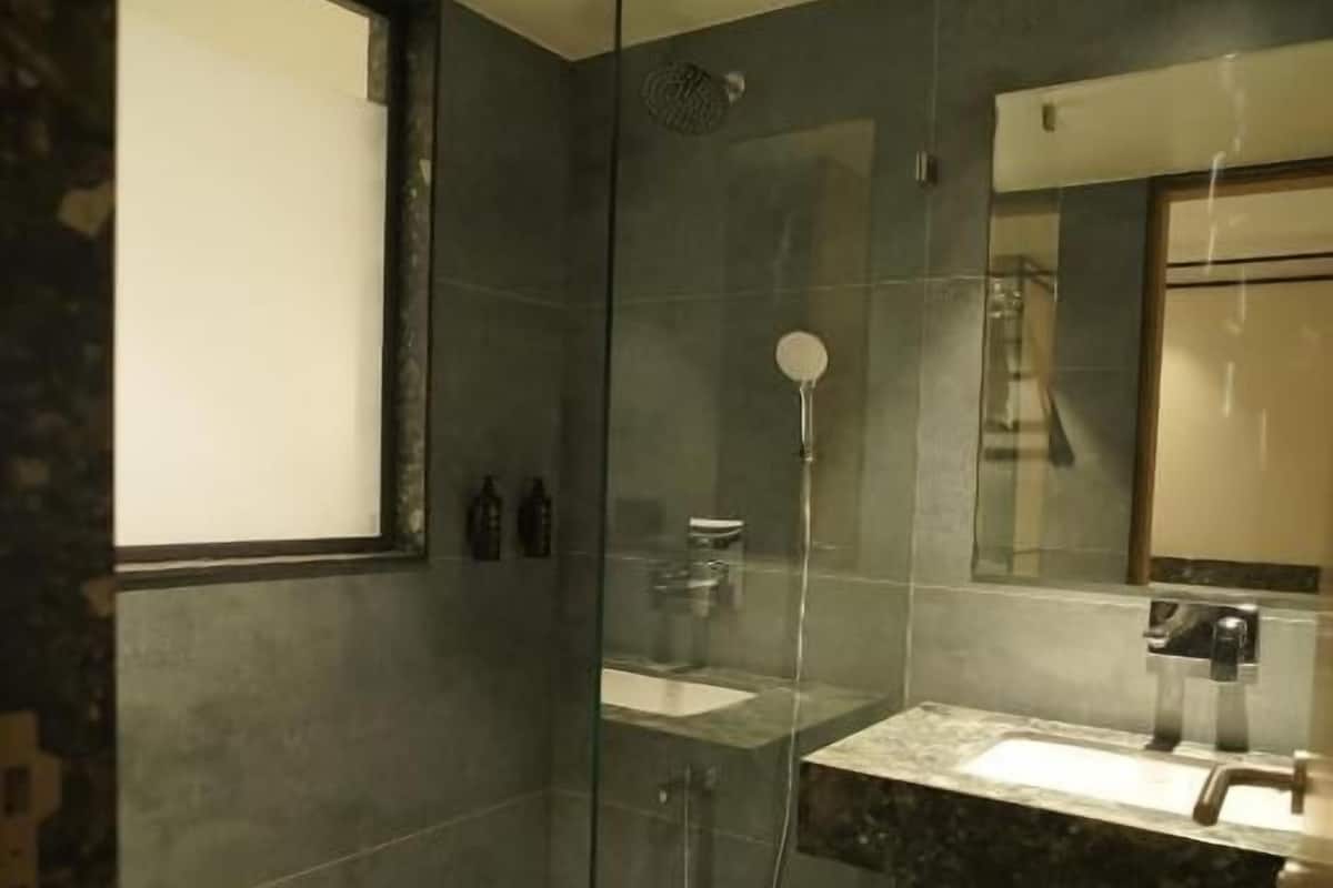 A modern bathroom with a glass shower enclosure, a sink with a marble countertop, and a large mirror above the vanity.