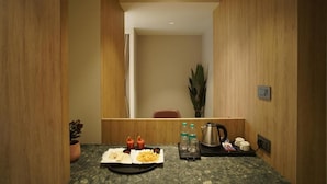 Ein Hotelzimmer mit Holzvertäfelung, einem kleinen Tisch mit Frühstücksangeboten, einer Pflanze und einem Wasserkocher.