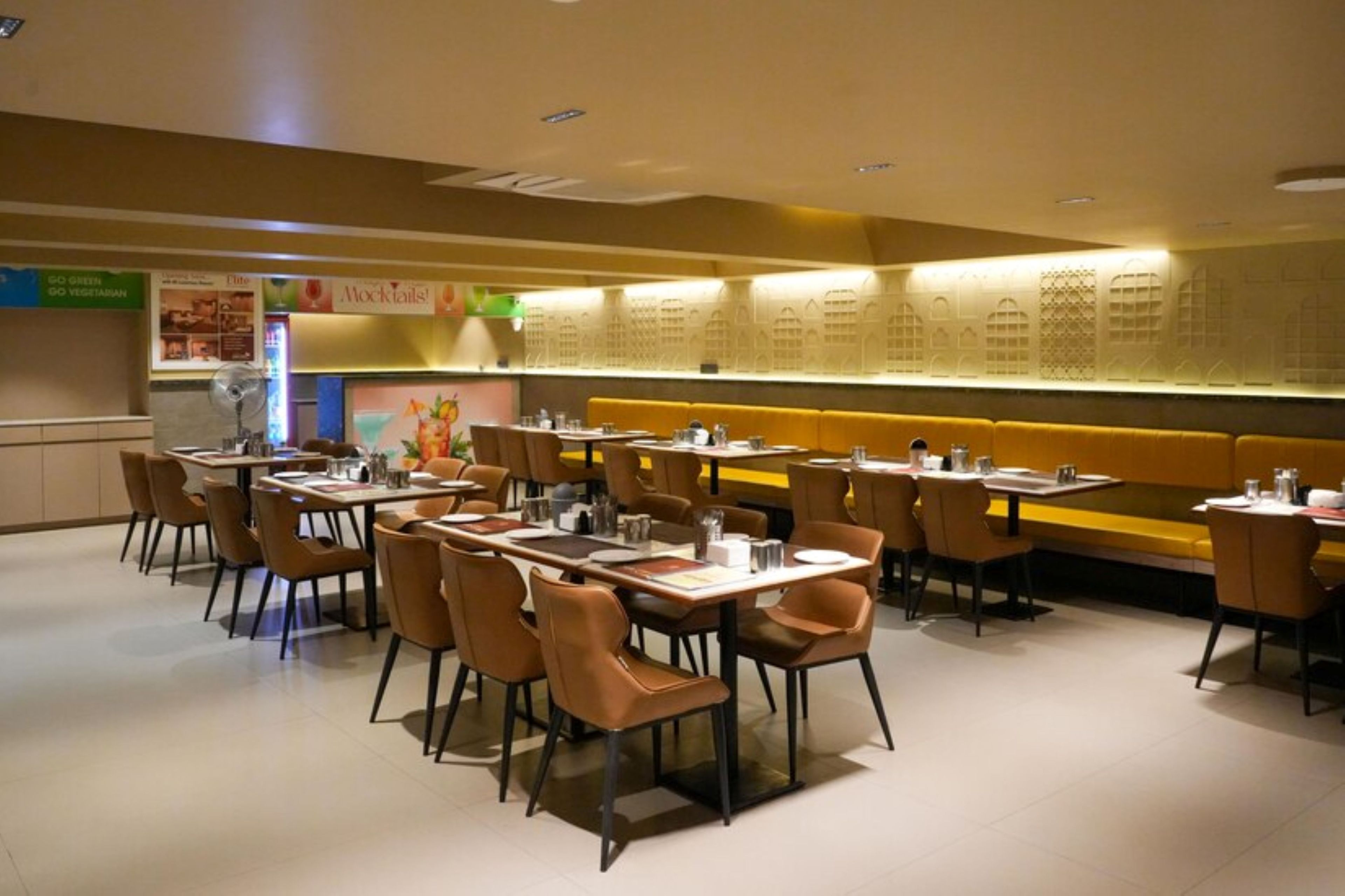 A restaurant with booths and tables, a menu board, and a wall with a pattern.