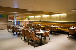 A restaurant with booths and tables, a menu board, and a wall with a pattern. - HOTEL SANKET ELITE (Malegaon)
