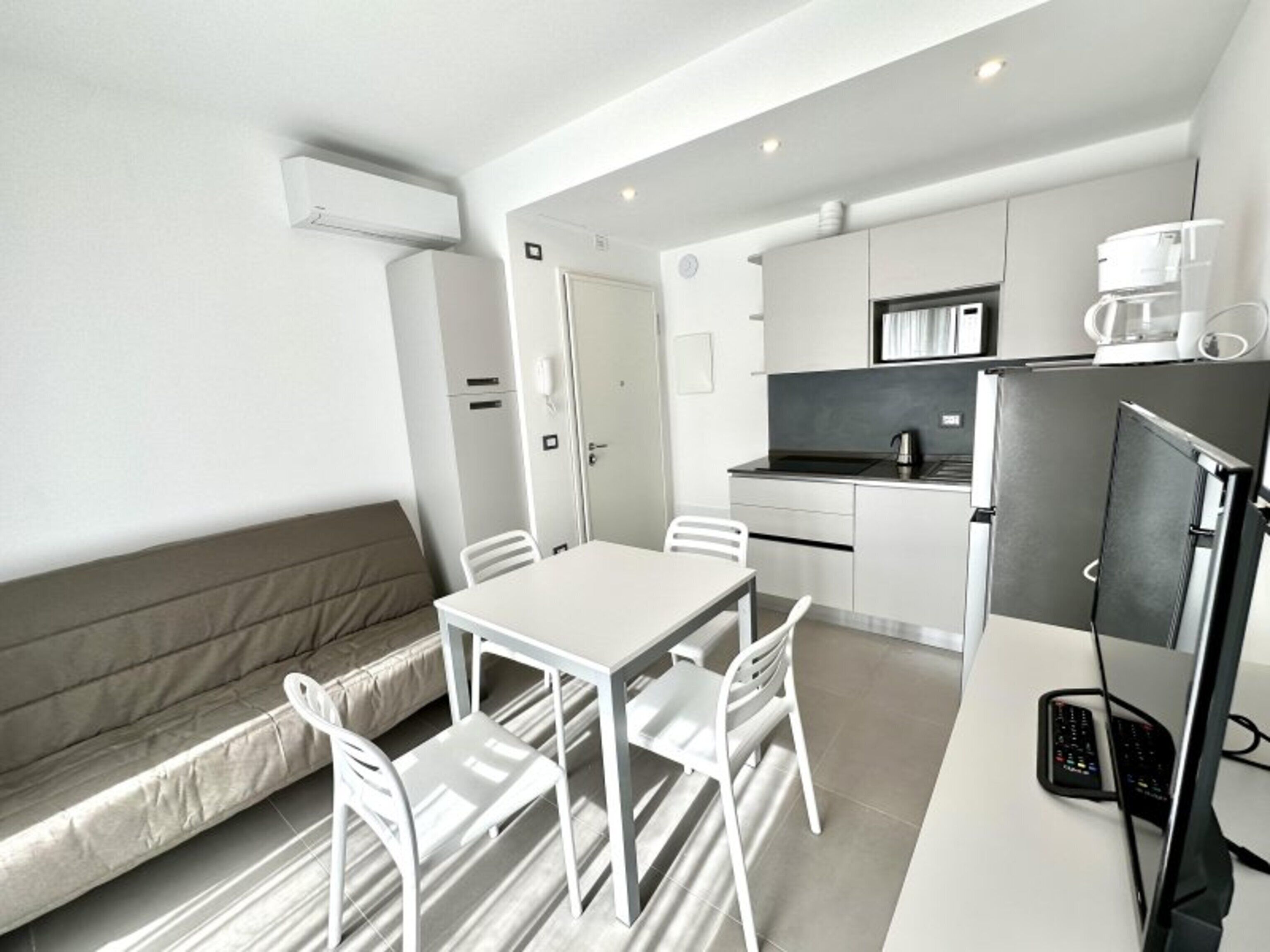 A modern kitchen with a refrigerator, microwave, and coffee maker.