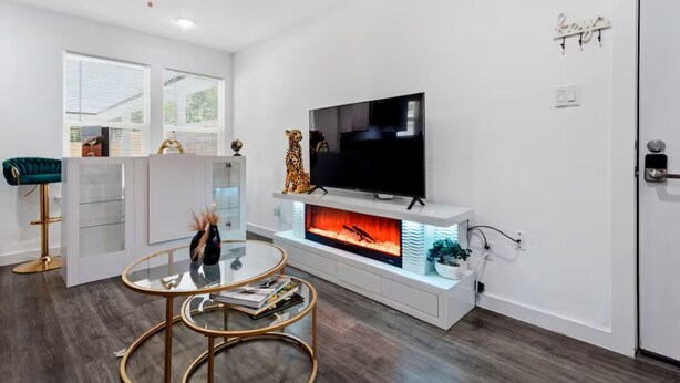 A modern living room with a flat-screen TV, a fireplace, and a glass coffee table. - Downtown Houston Modern Cozy Townhouse with Free Parking,WIFI and Near Airport (Houston)