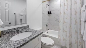 A bathroom with a marble sink, a toilet, a bathtub, and a shower curtain with a pattern. - Downtown Houston Modern Cozy Townhouse with Free Parking,WIFI and Near Airport (Houston)