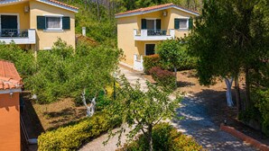 Due edifici gialli con balconi, immersi nel verde e circondati da alberi.
